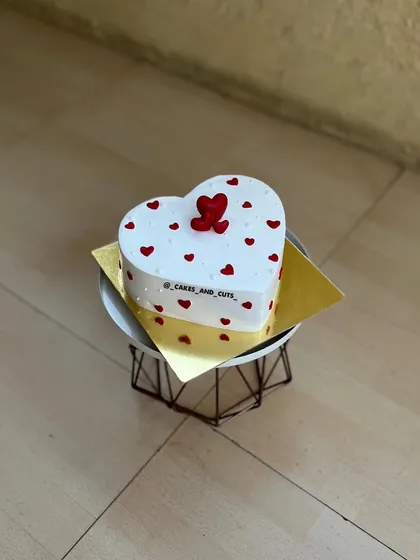 A heart-shaped cake decorated with small red hearts, a classic choice for a romantic celebration.