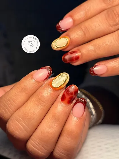 Another look at this fall-inspired set, showing how the red tortoiseshell, gold chrome, and French tip nails work together.