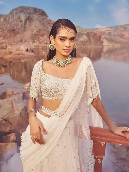 A close-up of the embellished blouse and belted waist of the ivory sharara-saree, showcasing its flattering details.