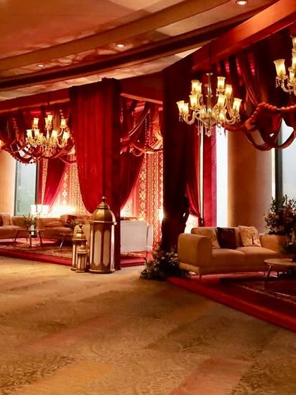 A wide view of the luxurious lounge area, with deep red drapes, elegant chandeliers, and comfortable seating arranged for conversation.