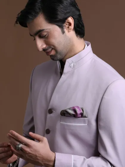 A close-up of the lilac bandhgala, highlighting the subtle texture of the fabric and the unique collar detail. The patterned pocket square adds a touch of personal flair.