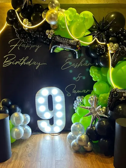 A full view of the "Game On" birthday setup, showcasing the neon-outlined backdrop, the bright marquee '9', and the vibrant green and black balloon garland. This decor is perfect for creating an immersive gaming zone for the party.