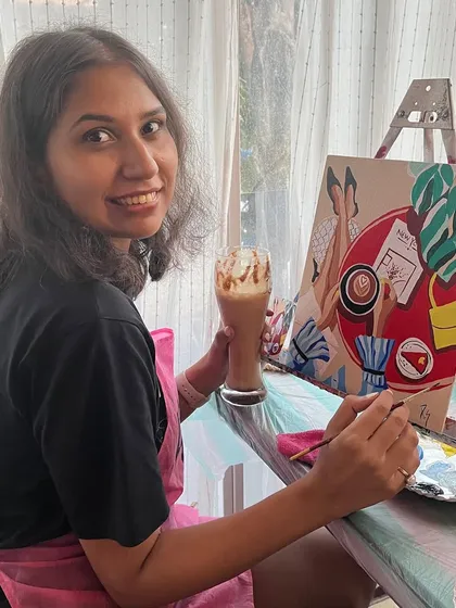 A participant enjoying her coffee while working on her chic painting. The cafe workshops are a perfect blend of relaxation and creativity.