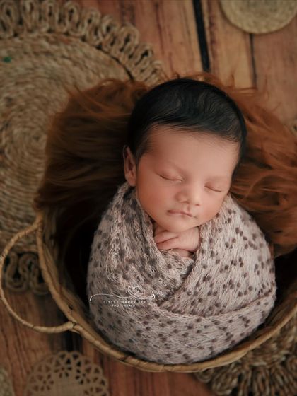 A little bundle of joy in a basket. The top-down angle and the surrounding jute mats create a beautiful, textured, and rustic composition.