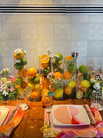 This summer birthday tablescape is bursting with freshness, using tall glass vases filled with whole lemons, limes, and oranges, interspersed with delicate floral bouquets.