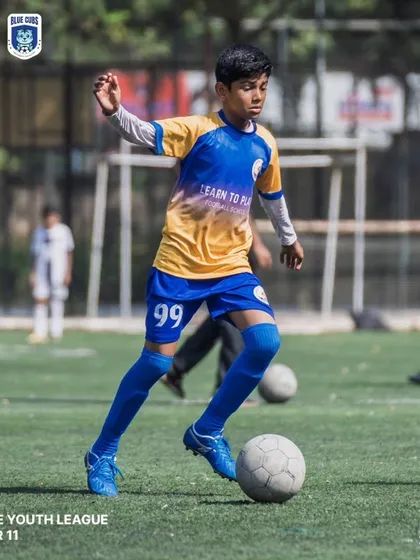 A U11 player dribbling the ball with determination during a competitive league match.
