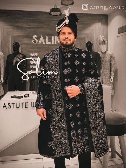 A groom dressed in a black velvet sherwani with intricate silver floral embroidery. The matching stole and safa complete this powerful and elegant wedding day look.