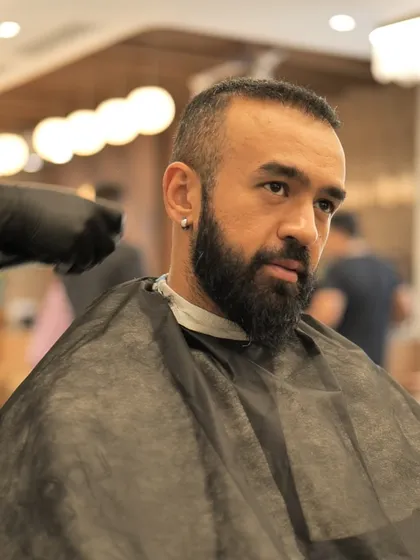 A close-up of a man getting his beard shaped, highlighting the attention to detail in our men's grooming services.