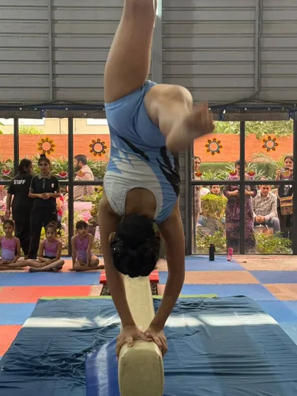 The focus and precision of a balance beam routine during a competition. This is what our gymnasts train for, performing with confidence in front of judges and an audience.