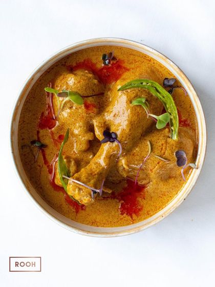 A bowl of our comforting Chicken Dum Curry. The rich, creamy gravy is infused with traditional spices and garnished with a fresh green chili for a hint of heat.