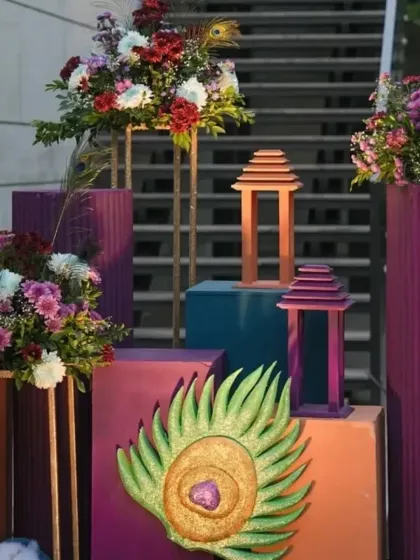 Elegant decor elements for a modern Krishna-themed party. We used rich colors, floral arrangements, and peacock feather motifs to create a sophisticated yet traditional look.