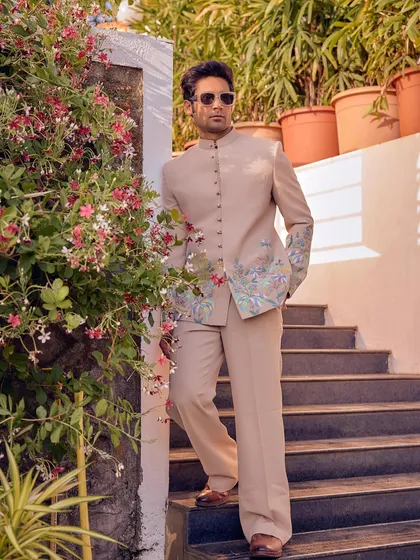 Crafted for compliments, this beige bandhgala suit with floral embroidery on the sleeves is designed to stand apart. It brings an effortless elegance to any celebration.