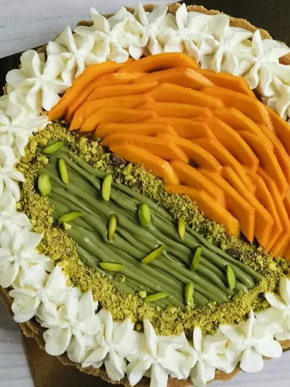 This close-up highlights the textures of the fresh mango, creamy pistachio spread, and the surrounding whipped cream topping.