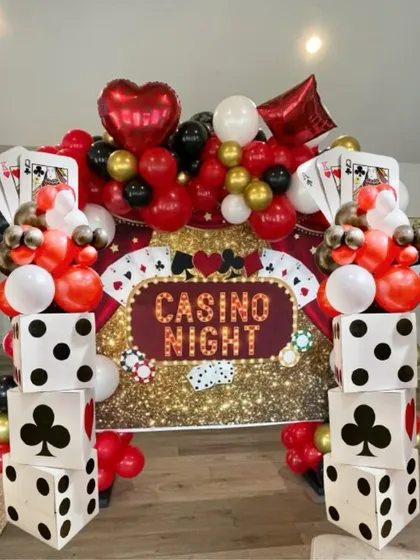 A full casino night setup ready for action. This backdrop features a sequin wall, a custom "Casino Night" sign, and our signature dice panel columns topped with red, black, and gold balloons.