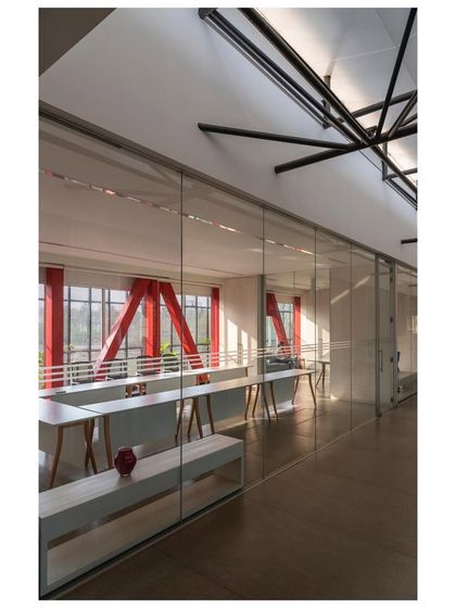 The 'Hoverspace' project, an award-winning design, showcases how a new structure can be added above an existing one. The glass-walled office spaces offer panoramic views, with the red structural trusses visible from the interior.
