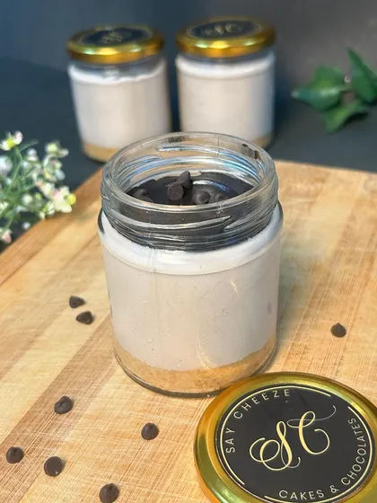 A chocolate cheesecake jar, with a biscuit crust and a creamy, chocolate-infused filling, topped with chocolate chips.