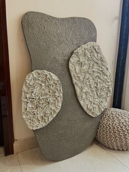 A 3ft x 2ft piece for a Mumbai home, featuring a grey textured base with two patches of delicate, fabric-like ruffles. This work explores the contrast between rough and soft textures.