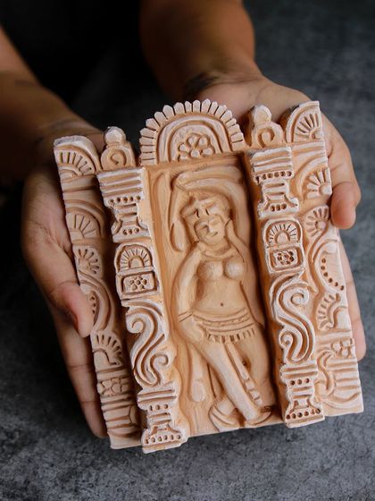 A student proudly displays their finished Salabhanjika relief tile, a classic Indian sculptural motif brought to life in clay.