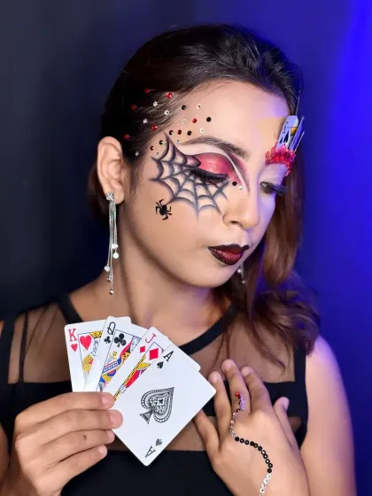 This pose showcases the full concept, with the model holding playing cards that match the ones used in the makeup.