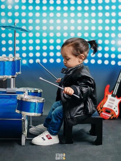 A wide shot of the rockstar set, complete with a drum kit, guitar, and speakers.