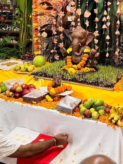 Preparing the prasad and offerings for the puja. The table is laden with fruits, sweets, and flowers, all arranged beautifully before the idol.