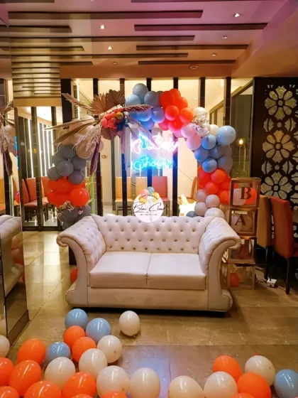 A stylish baby shower photo corner with a balloon arch and a classic white sofa.
