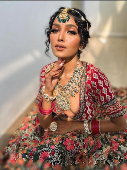 A floral printed lehenga paired with a red embroidered blouse and heavy polki jewellery. A modern twist on a bridal look.