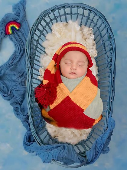 A colorful and whimsical setup with a baby nestled in a whale-shaped basket. The rainbow detail adds a touch of magic to this creative newborn photo.