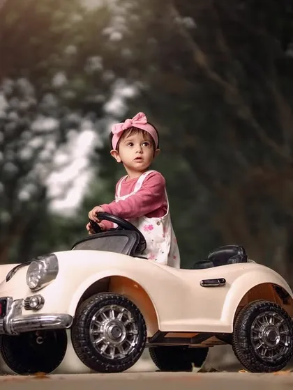 A little girl enjoying an autumn drive in her vintage toy car. The path lined with trees creates a beautiful, scenic backdrop for this portrait.