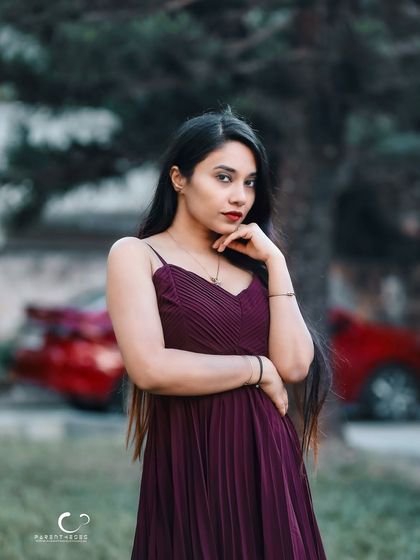 A confident and direct portrait with a pop of red from the car in the background. The composition is modern and stylish.