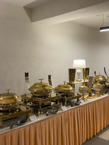 A classic and elegant indoor buffet arrangement. This setup uses a simple table skirt paired with our luxurious gold chafing dishes, vases, and table lamps, suitable for formal luncheons or house parties.