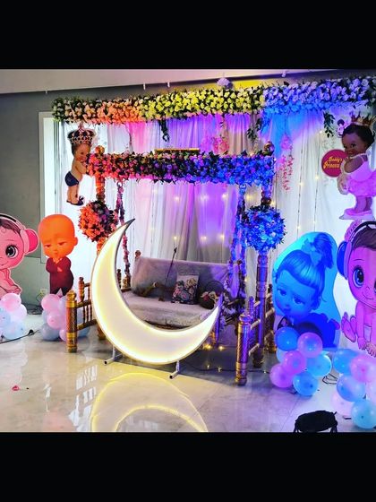 A close-up view of the baby shower stage, highlighting the decorated swing, lighted moon, and the variety of cartoon cutouts.