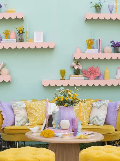 A vibrant yellow sofa set against a mint green wall with pink scalloped shelves, creating a picture-perfect and colorful photo corner.