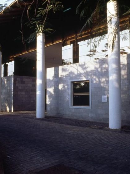 The exterior of the LMW Headquarters in Coimbatore, where stone-clad walls and prominent columns define the edges of the courtyard spaces within. The architecture uses a vocabulary of solid and void to create a rhythm of open and enclosed areas.