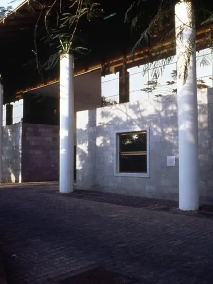 The exterior of the LMW Headquarters in Coimbatore, where stone-clad walls and prominent columns define the edges of the courtyard spaces within. The architecture uses a vocabulary of solid and void to create a rhythm of open and enclosed areas.