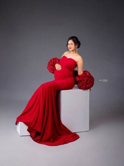 A gentle, downward glance can create such a serene and loving portrait. Here, the focus is on the connection between mother and baby, highlighted by the striking red gown.