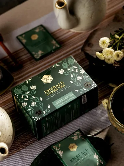 A moody, rustic flatlay for Mittal's Emerald Green Tea. The composition on a striped cloth with traditional pottery gives the product an organic and artisanal feel.