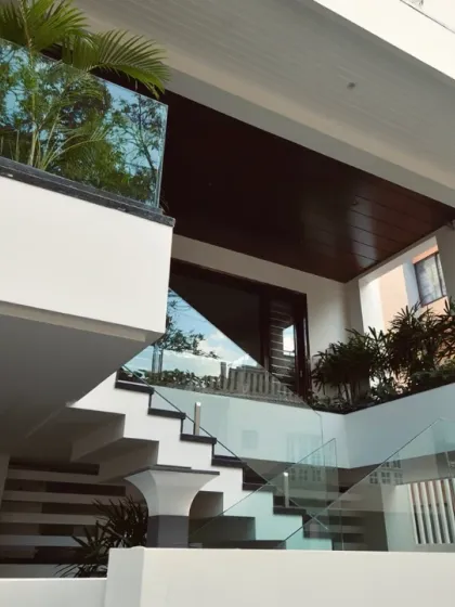A detail of the villa's entrance, where an external staircase seems to float, guided by glass railings. Planter boxes are integrated into the structure, infusing the architecture with greenery.