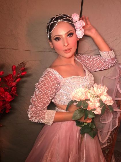 The 'Rose' look, featuring a beautiful pastel pink gown and a floral headpiece. The makeup is soft, golden, and glowing.
