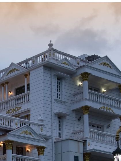 A close-up of the palace facade at dusk. The warm interior lighting contrasts with the cool evening sky, highlighting the building's elegant silhouette and classical details.
