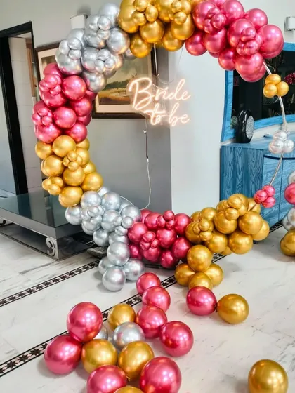 This vibrant balloon ring for a bridal shower uses a mix of hot pink, gold, and silver metallic balloons. The "Bride to be" neon sign at the center ensures the bride-to-be is the star of every photo.