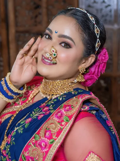 A joyful expression from a client loving her traditional makeover, complete with a classic nath and choker.