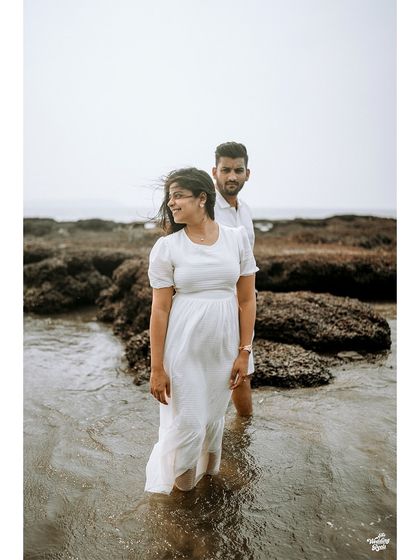 A beautifully composed shot of a couple standing in the water, with the bride looking off-camera, creating a candid and thoughtful portrait.