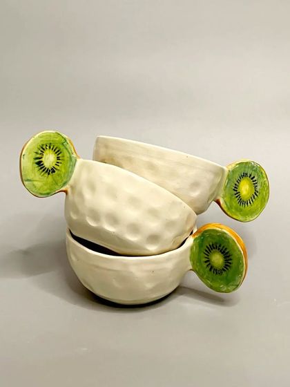 A stack of my kiwi-inspired mugs. The textured surface and hand-painted kiwi handle make this a fun and artistic piece for your everyday routine.