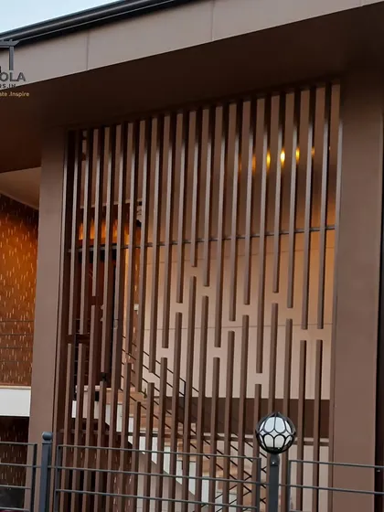 This image shows a building exterior with vertical metal slats used as a decorative and privacy screen. The warm, bronze-colored finish adds a touch of elegance and modernity to the facade.