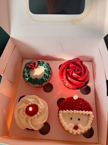 My special Christmas-themed cupcakes. This box of four includes designs like a Santa hat, a wreath, a red rose, and a candle, all hand-piped with buttercream to bring some festive cheer.