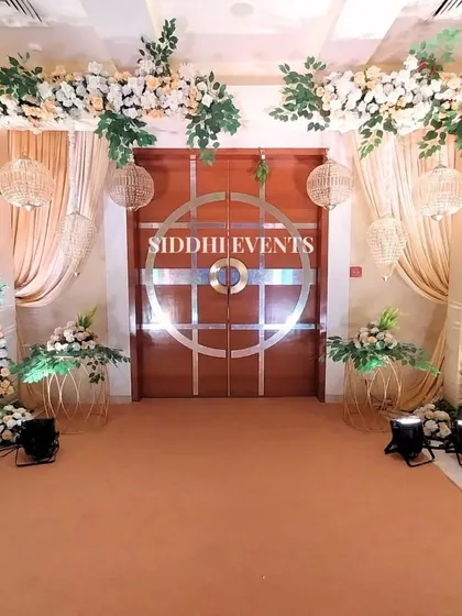This stunning entrance features a floral archway of lush white blooms and greenery, accented with hanging wicker ball lanterns for a touch of rustic elegance.