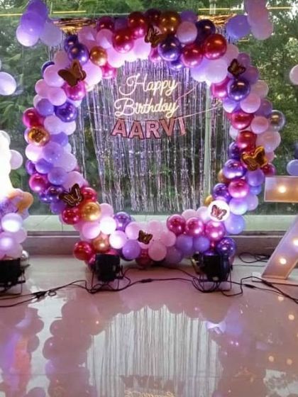 A magical princess party for Aarvi's 7th birthday. This setup features a stunning circular balloon arch in shades of purple, pink, and chrome, with butterfly accents and a shimmering curtain backdrop. A large light-up number '7' and a princess cutout complete the fairytale scene.