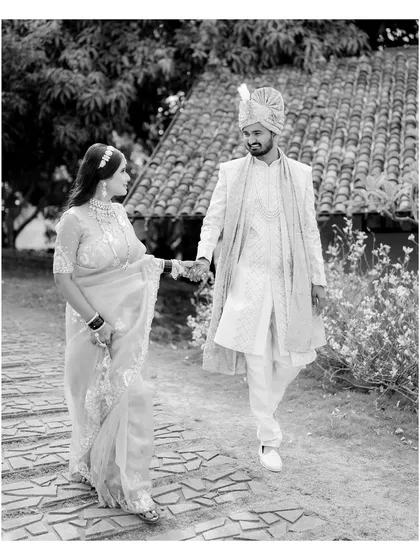 A classic black and white portrait of Vicky and Aishwarya walking hand-in-hand. The natural setting and their elegant attire create a timeless image that feels like a scene from a vintage film.