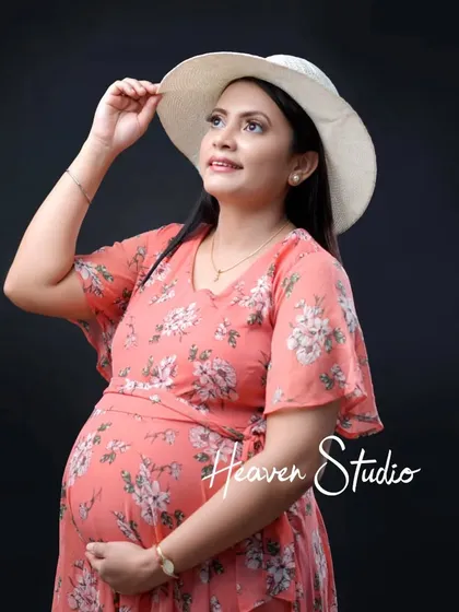 A lovely portrait in a floral print dress. The mother-to-be looks up thoughtfully, her expression full of hope and happiness for the future.